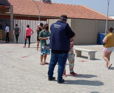 servidores entrevistam pessoas na fila para receber o kit merenda escolar