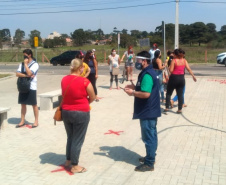 servidores entrevistam pessoas na fila para receber o kit merenda escolar