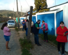 servidores entrevistam pessoas na fila para receber o kit merenda escolar