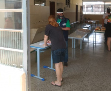 servidores entrevistam pessoas na fila para receber o kit merenda escolar