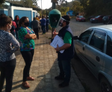 servidores entrevistam pessoas na fila para receber o kit merenda escolar