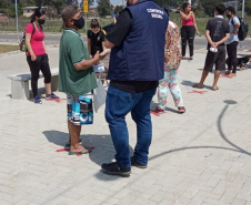 servidores entrevistam pessoas na fila para receber o kit merenda escolar