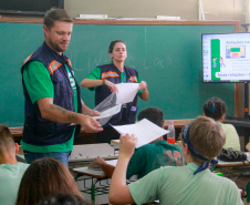 equipes distribuem formulários a alunos em pesquisa