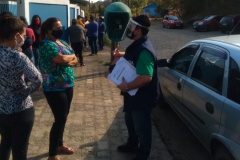 servidores entrevistam pessoas na fila para receber o kit merenda escolar