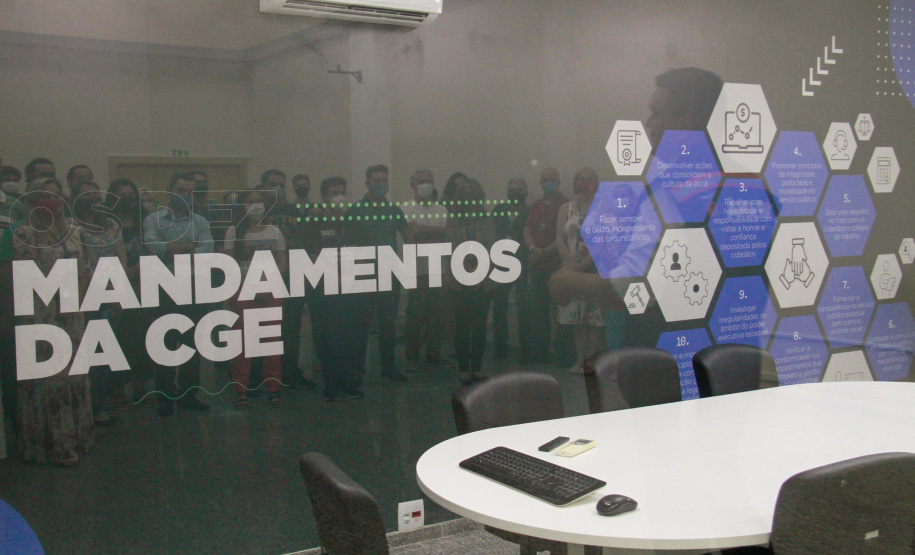 servidores reunidos na frente da sala com paredes de vidro