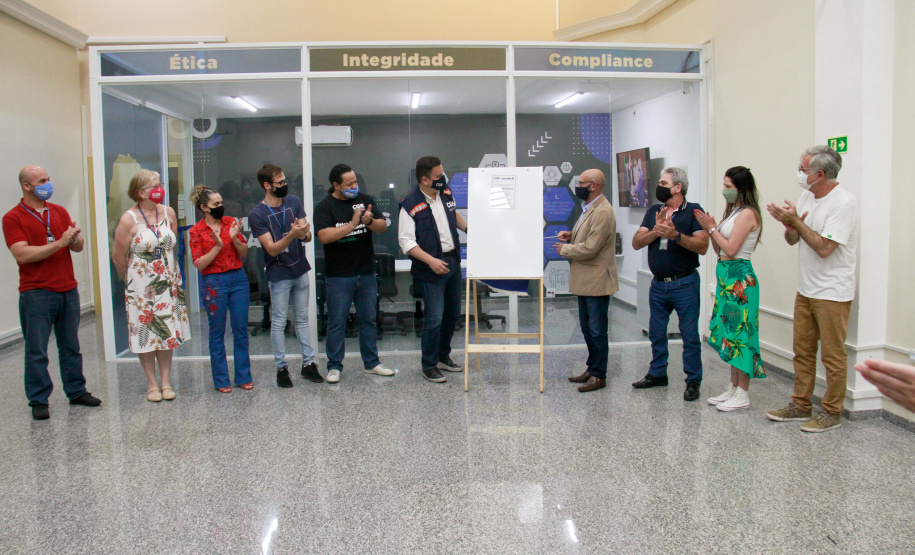 servidores reunidos na frente da sala com paredes de vidro