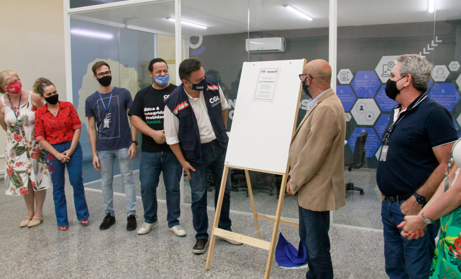 servidores reunidos na frente da sala com paredes de vidro