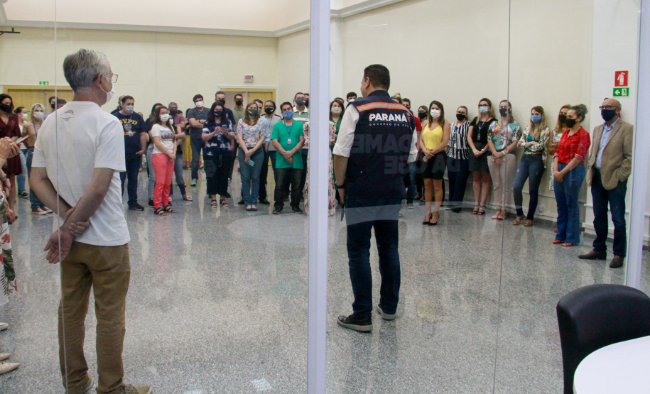 servidores reunidos na frente da sala com paredes de vidro